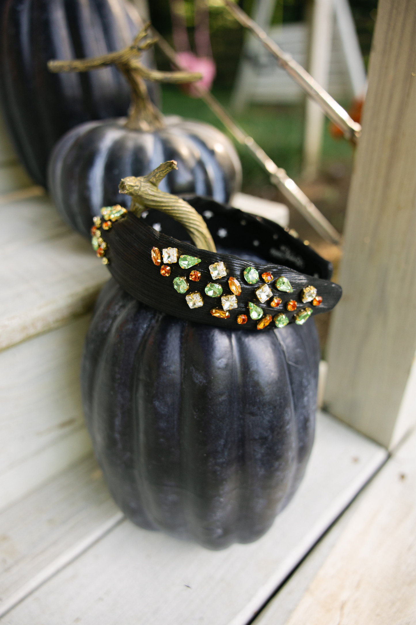 Decorative black pumpkin with colorful gemstones on a white surface