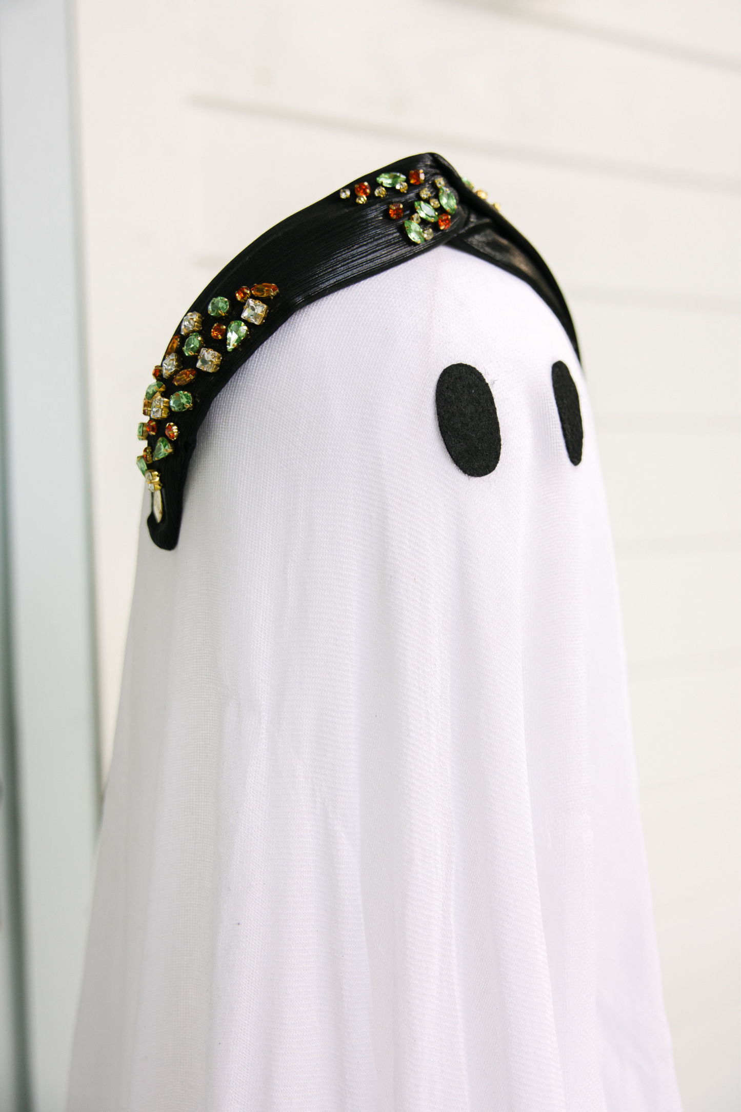 White ghost costume with black face and decorative headband on a white background