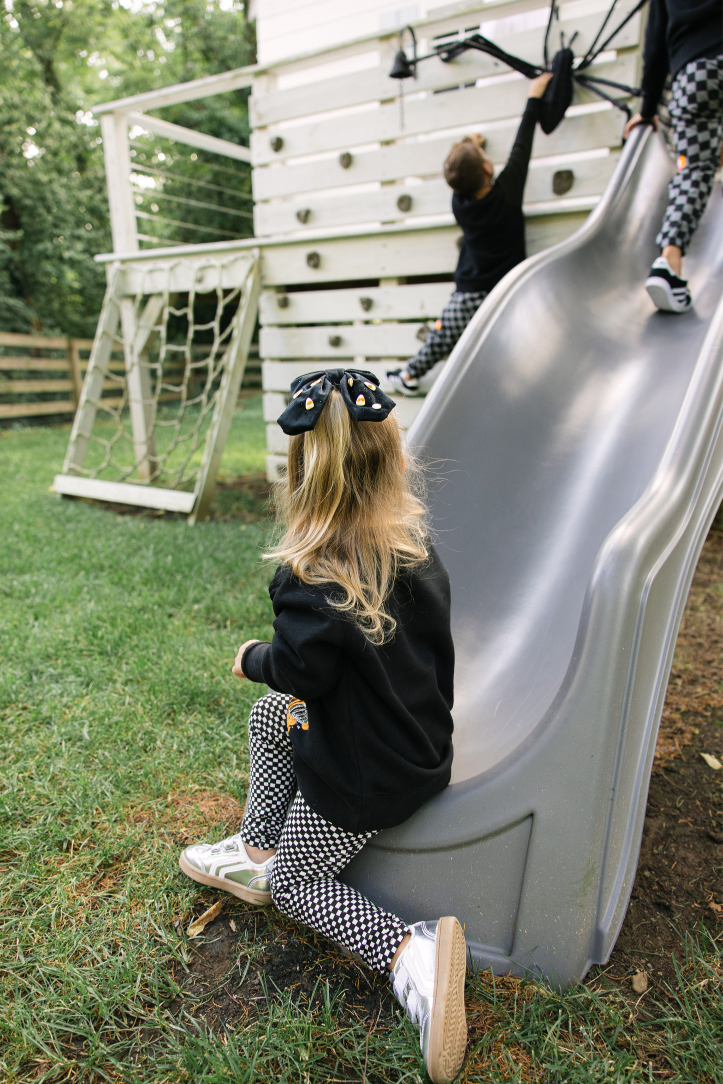 Child sliding down a playground slide with another child in the background.