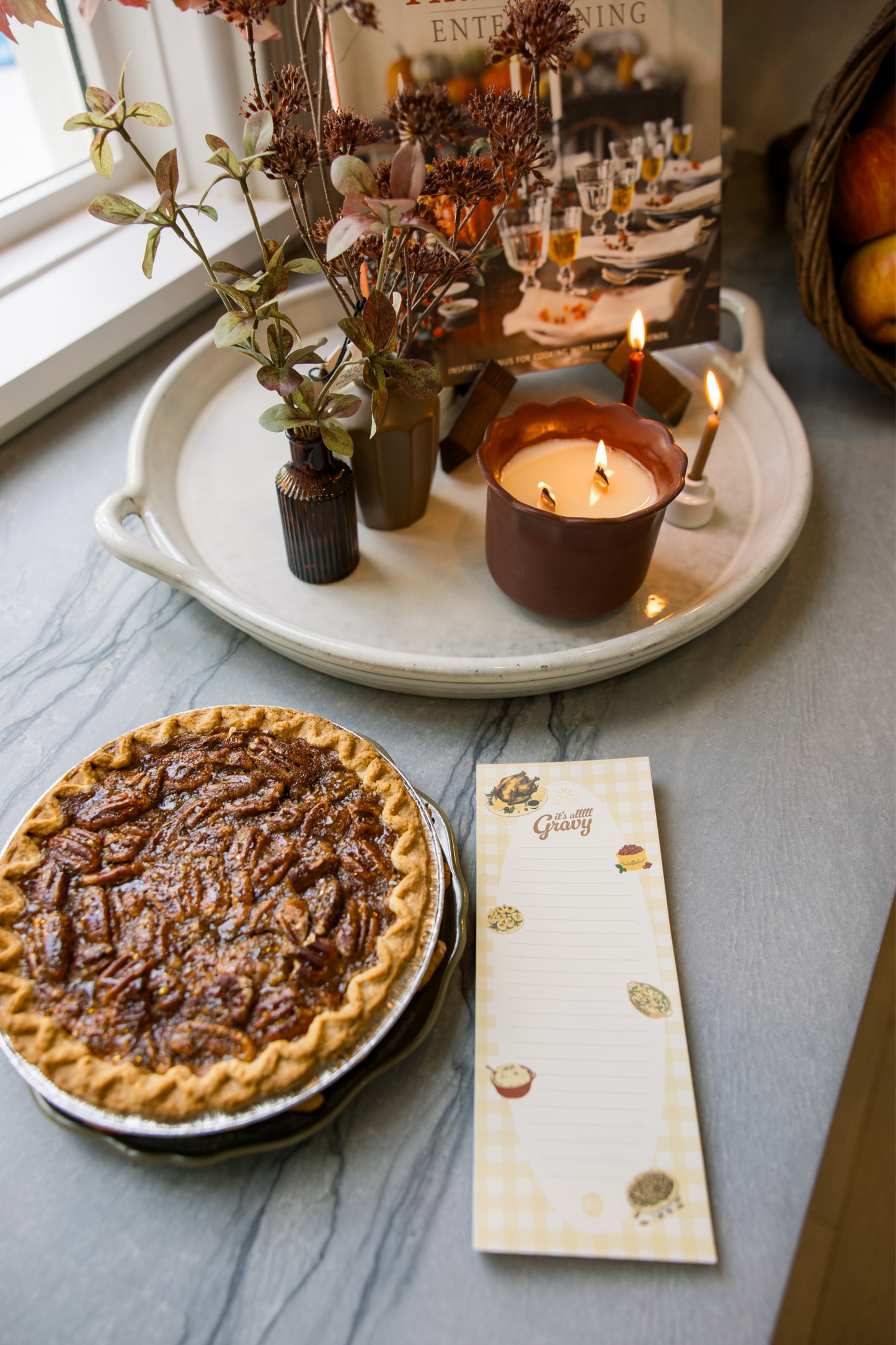 Pecan pie on a table with candles, a tray of flowers, and a card.
