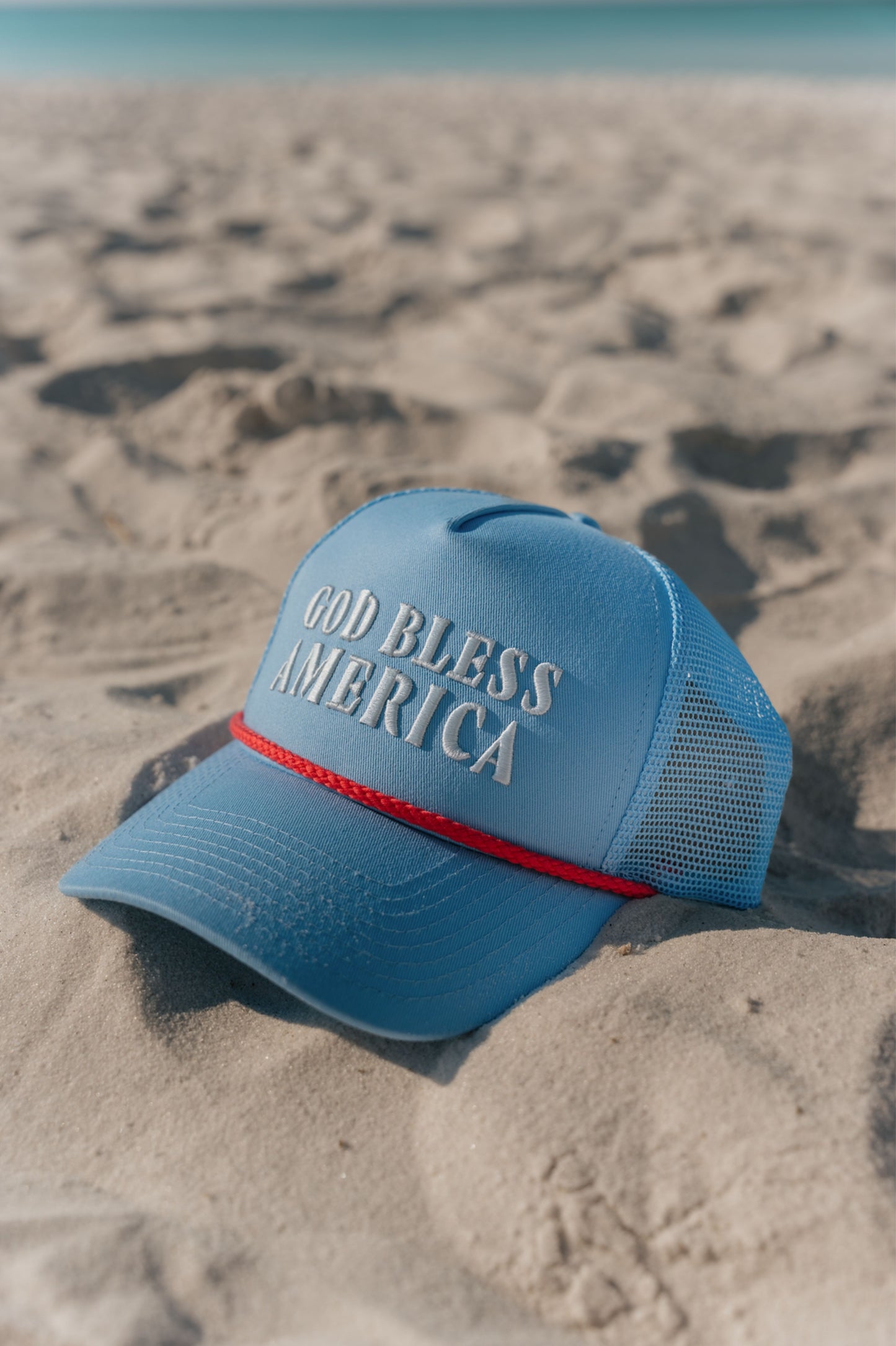 blue hat with god bless america on the front on the beach