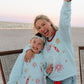 woman on beach at bonfire wearing light blue firework sweatshirt 