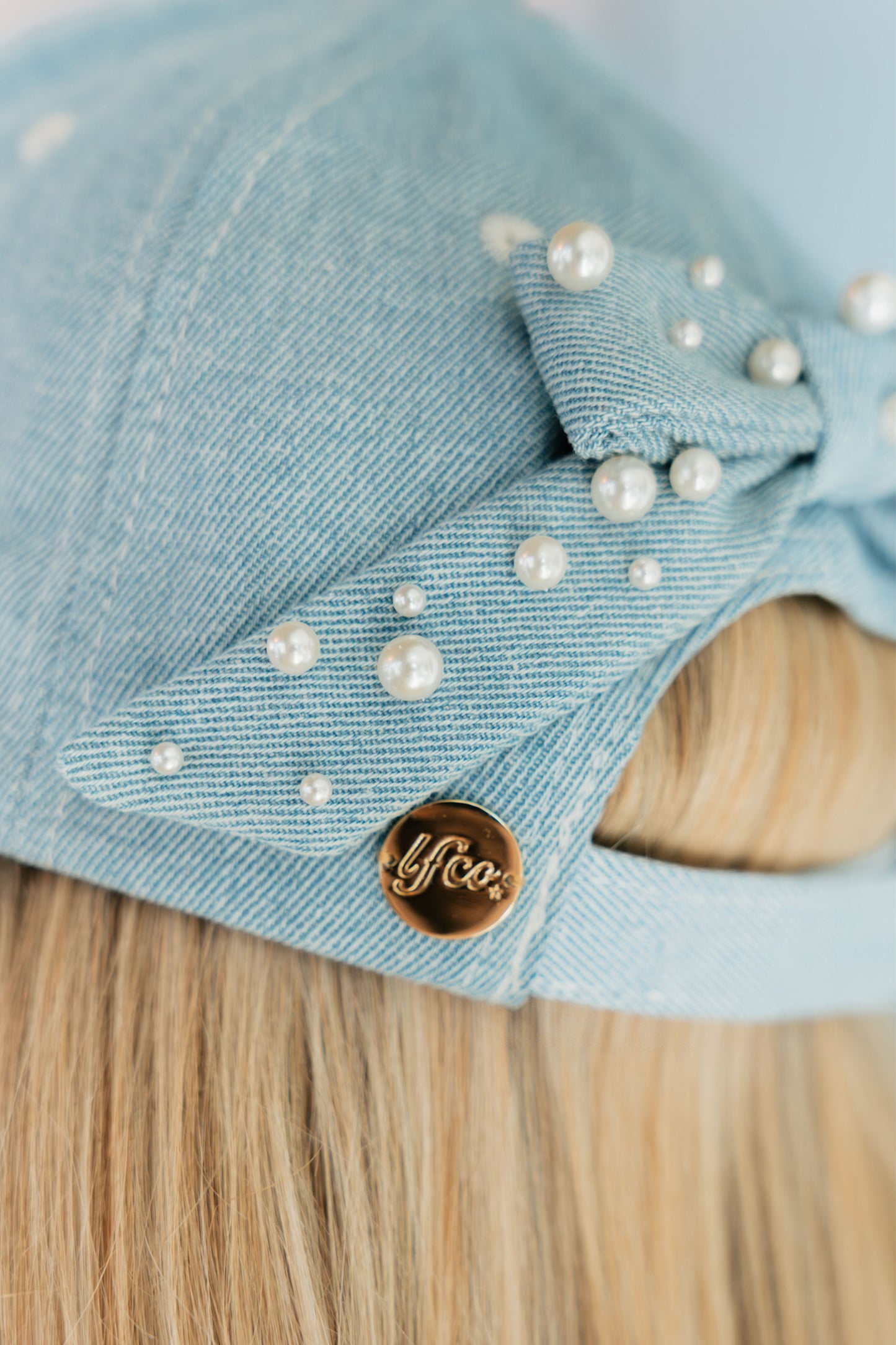 Light blue denim hat with pearls and a gold 'Lfco' logo on a denim surface.