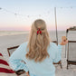red clip in blonde hair on beach 