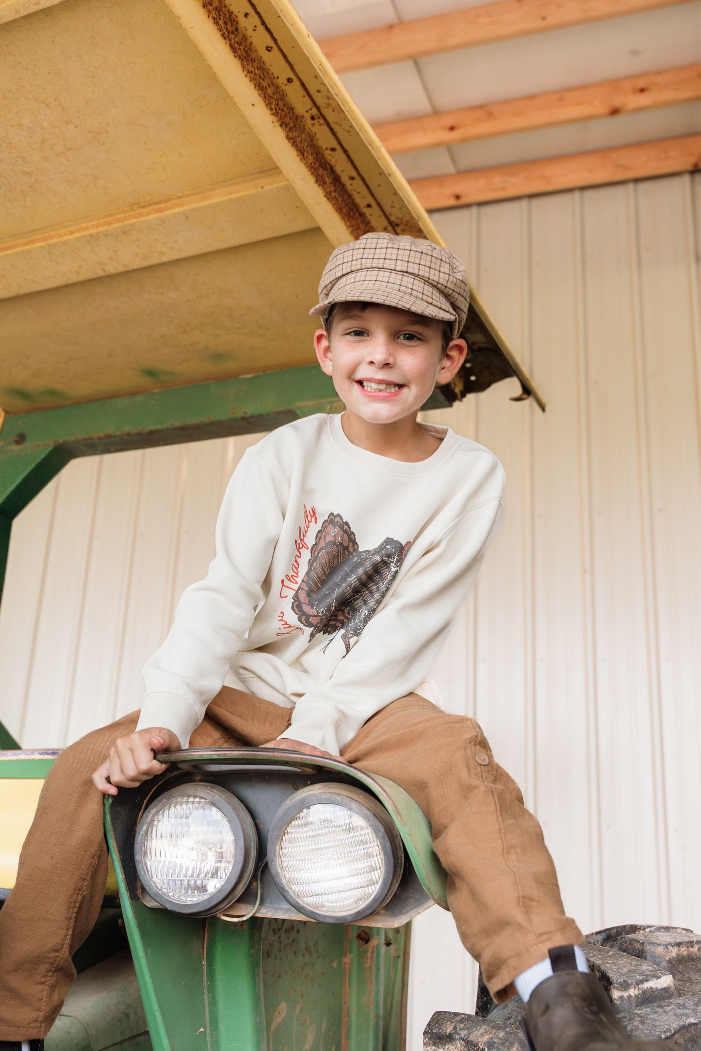 kid on a tractor wearing turkey sweatshirt