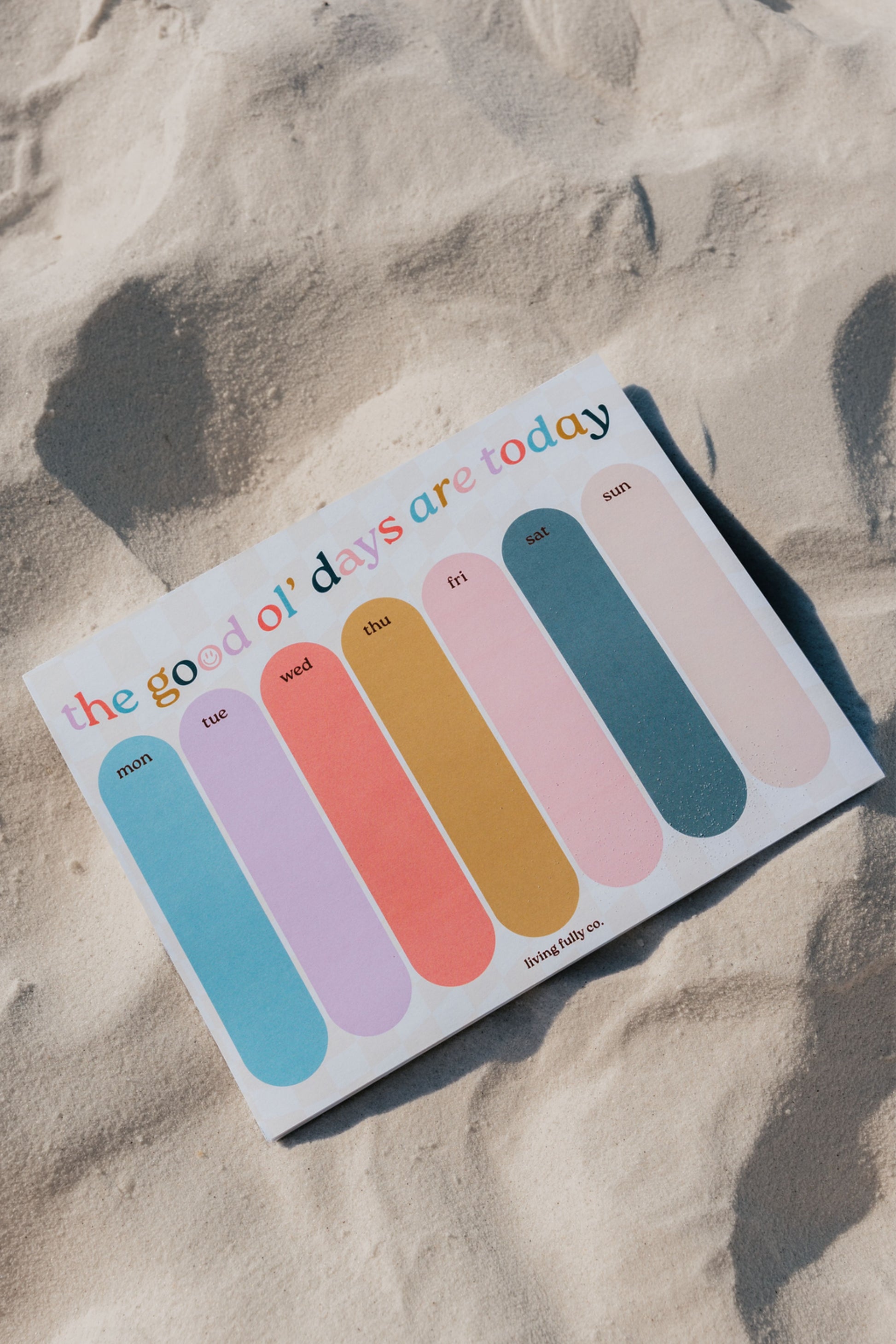 Colorful notepad with sticky notes on a sandy surface