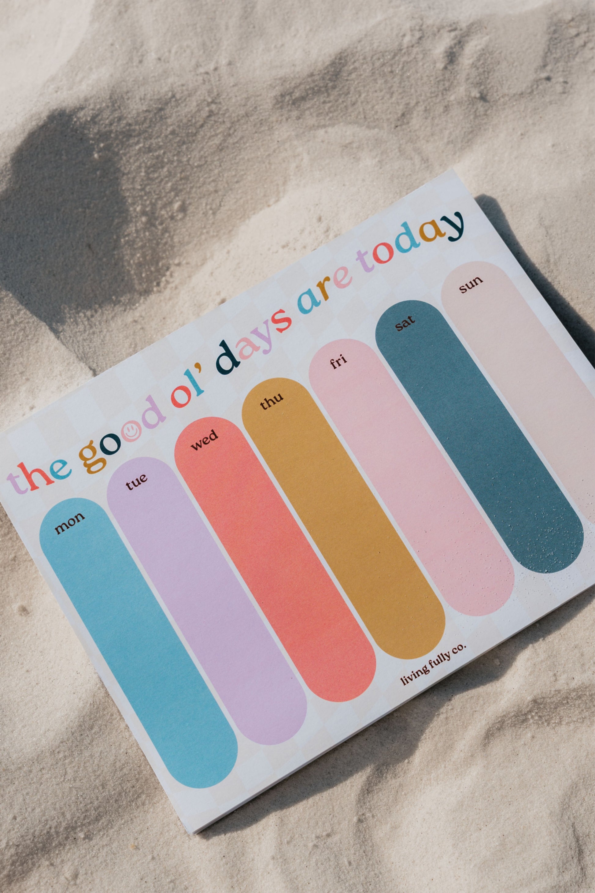 Colorful daily planner calendar on a sandy surface