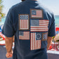 Man wearing a navy blue t-shirt with American flag designs on the beach.