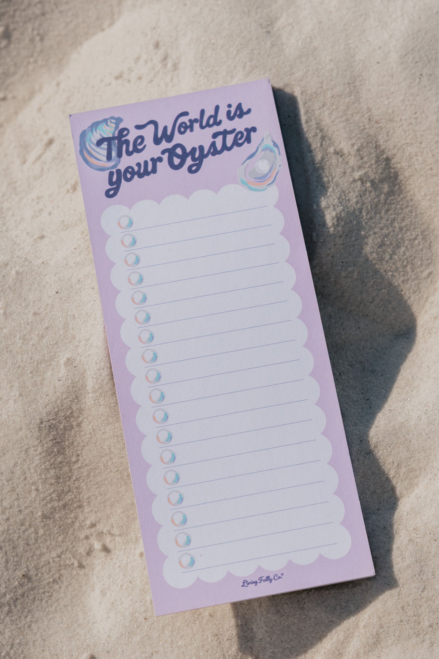 Notepad with 'The World is Your Oyster' text on a sandy background