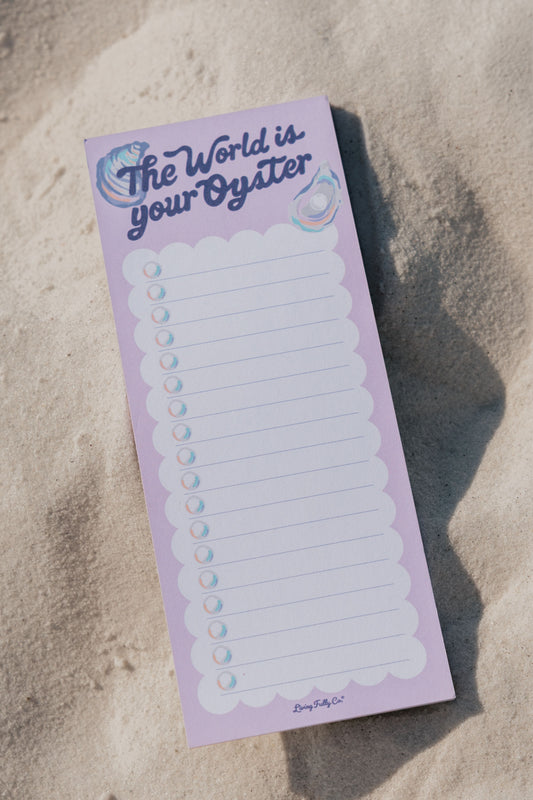 Notepad with 'The World is Your Oyster' text on a sandy background