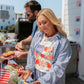 Man and woman preparing food outdoors with a barbecue grill in the background