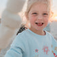little girl with marshmallows wearing sweatshirt on beach 