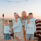 woman  and kids on beach at bonfire wearing light blue firework sweatshirt 