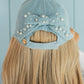 Light blue cap with a bow and pearls on a woman's head against a light blue background