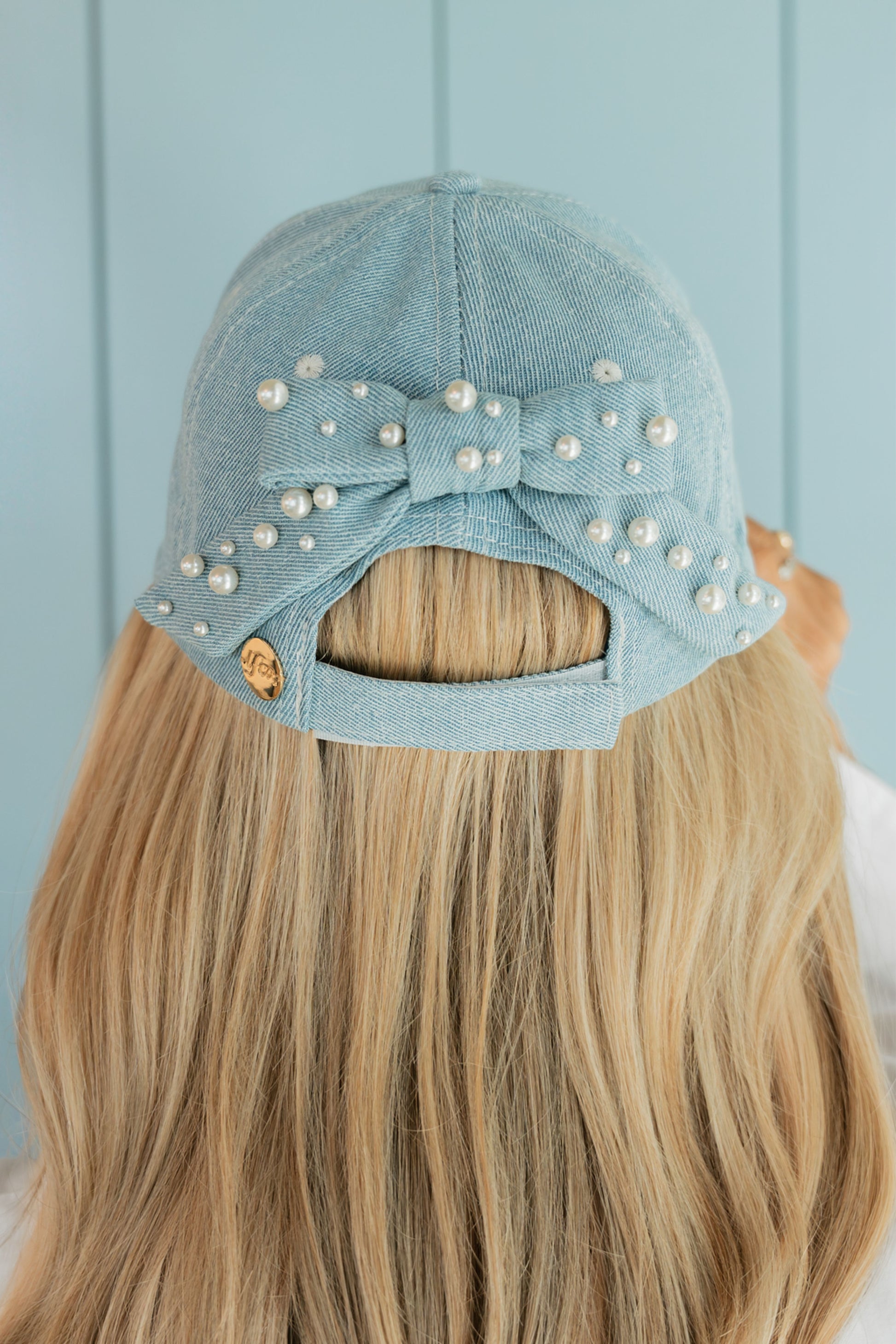 Light blue cap with a bow and pearls on a woman's head against a light blue background