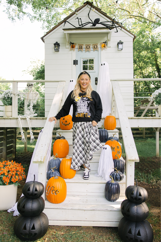 Person standing on a white playhouse decorated with Halloween pumpkins and decorations.