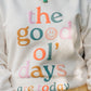 White sweatshirt with colorful text 'the good ol' days are today' worn by a person.