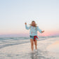 Person running on a beach with a colorful scarf belt and Living Fully Sweatshirt.