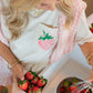 Woman washing strawberries in a sink wearing a classic LFC t-shirt featuring a strawberry design.