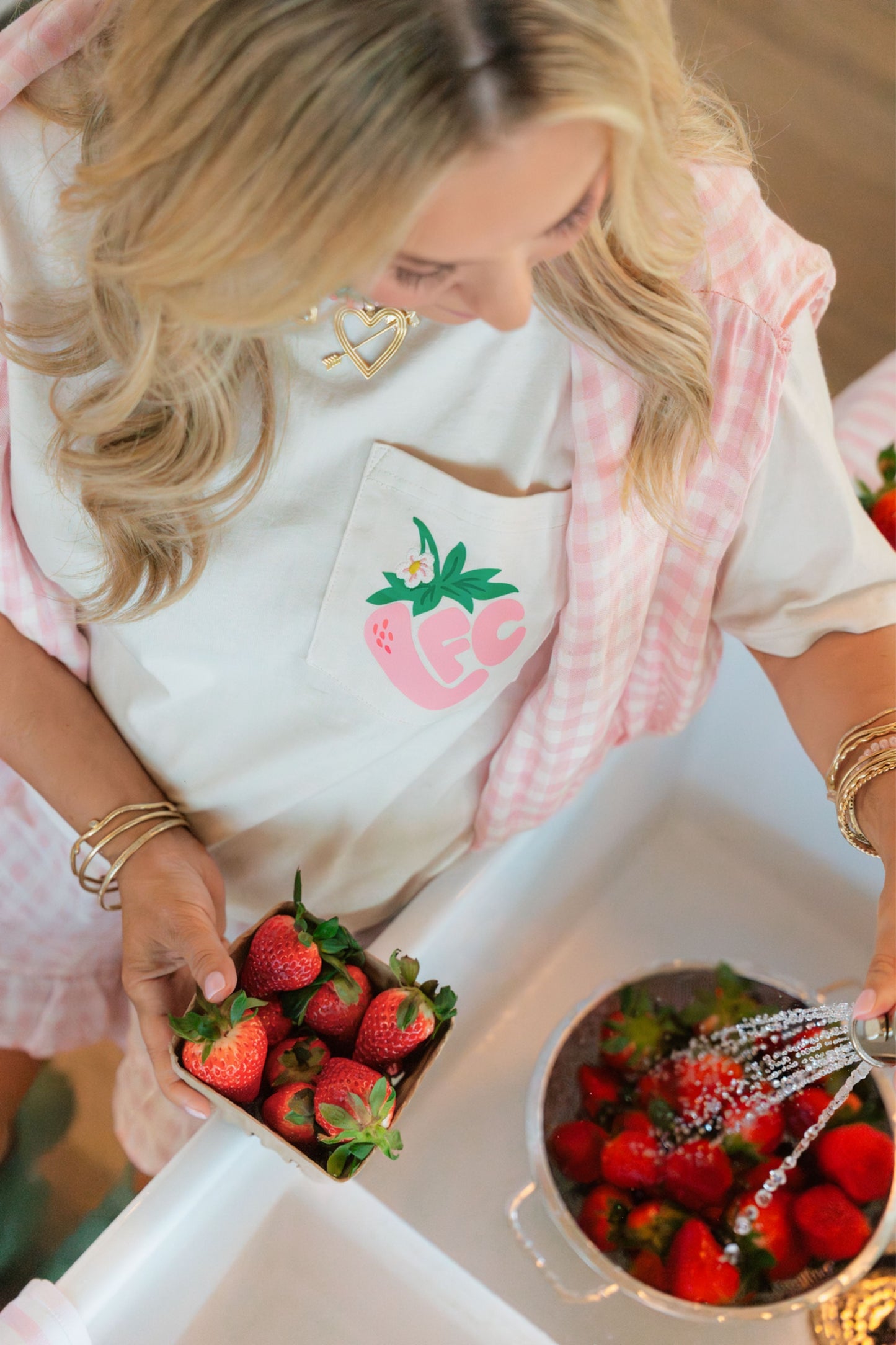 Woman washing strawberries in a sink wearing a classic LFC t-shirt featuring a strawberry design.