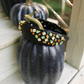 Decorative black pumpkin with colorful gemstones on a white surface