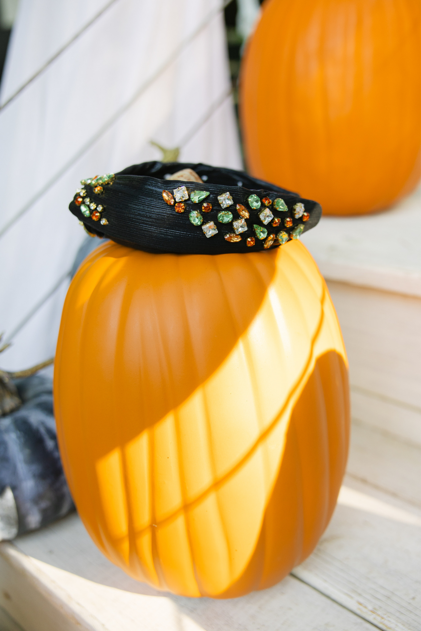 Decorative pumpkin with a black headband featuring colorful beads on a wooden surface.