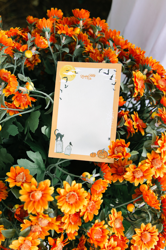 Halloween notepad resting on orange mums.
