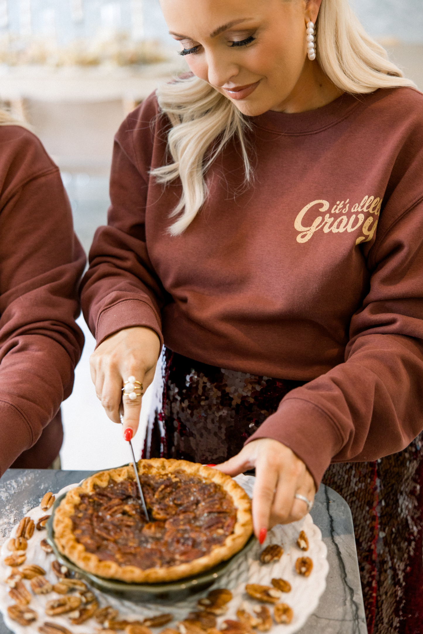 Person cutting a pie with another person wearing a sweatshirt with text in the background