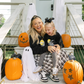 Woman and child sitting on a Halloween-themed playhouse with pumpkins and ghosts.