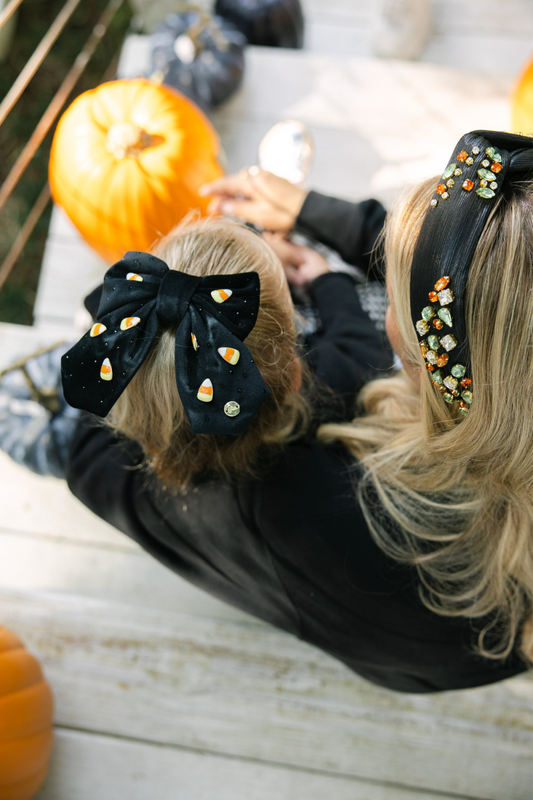 Woman and child wearing decorative hair accessories with pumpkins in the background.