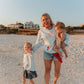Woman with two children on a beach at sunset all wearing LFC sweatshirts.