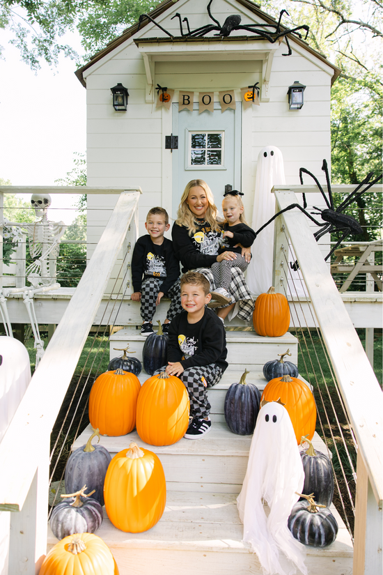 Family posing on a Halloween-themed staircase with pumpkins and decorations.