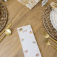 Table setting with a decorative place card on a wooden table.