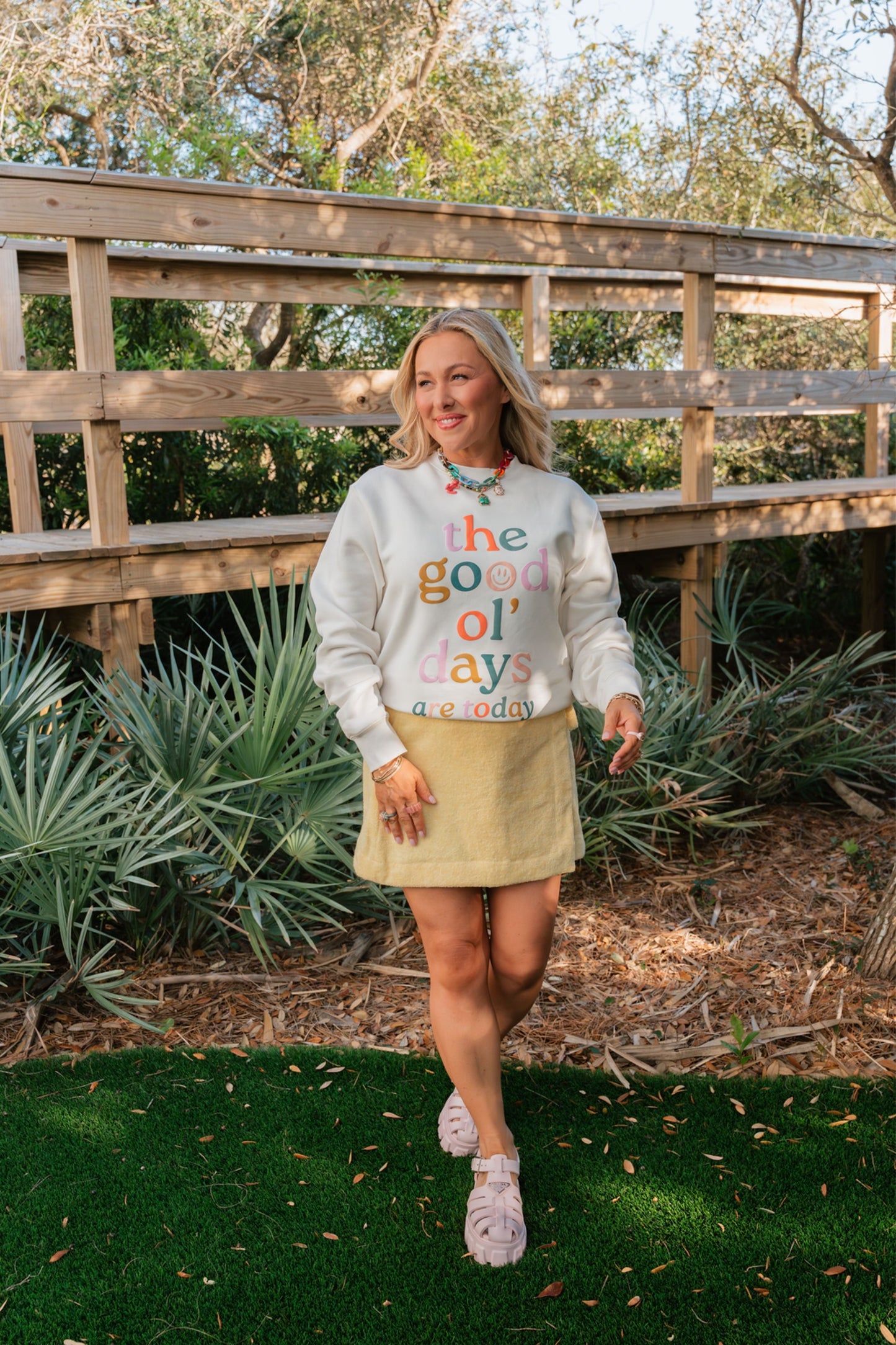 Woman wearing a colorful 'the good old days' sweatshirt in an outdoor setting.