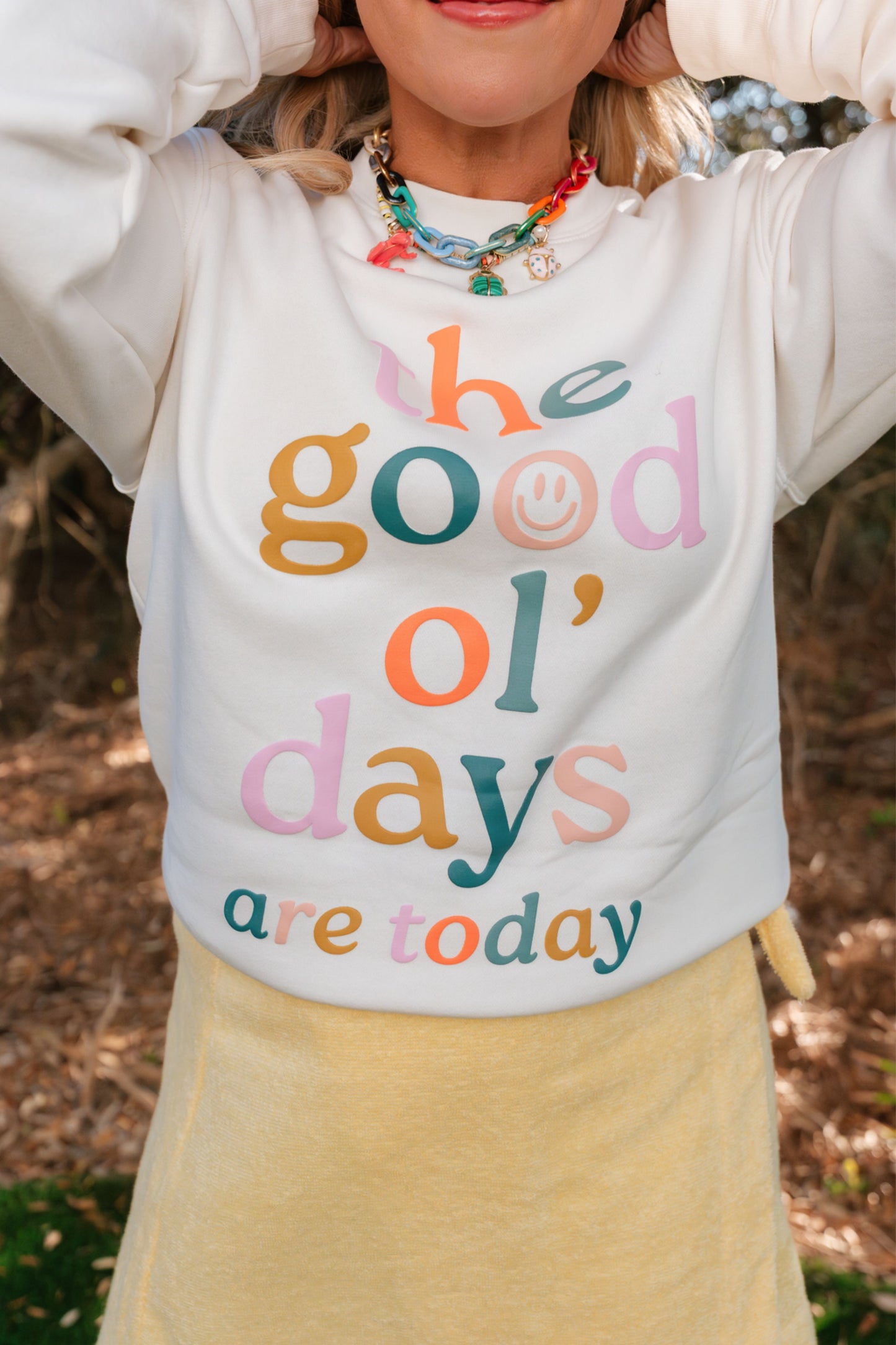 Person wearing a sweatshirt with 'The good ol' days are today' text in colorful letters.