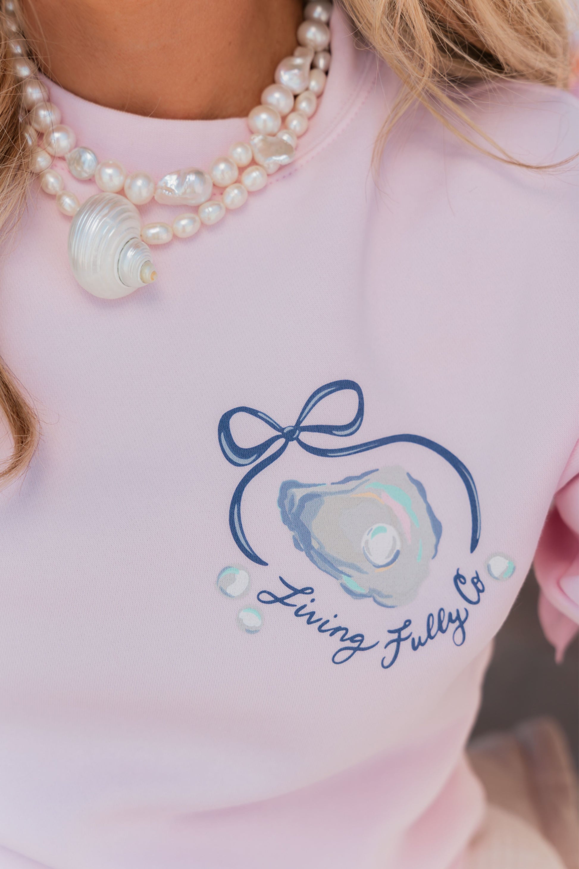 Pink shirt with a blue graphic and text 'Living Fully Co' worn by a person.