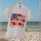 White t-shirt with floral design on a hanger against a beach background.