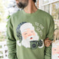 Man wearing a green sweater with a Santa Claus design and 'Tis the Season text.