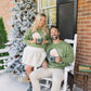 Couple sitting on a porch with a decorated Christmas tree in the background