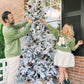 Two people decorating a Christmas tree on a porch.