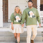 Man and woman walking on steps wearing green sweaters with Santa Claus graphics.