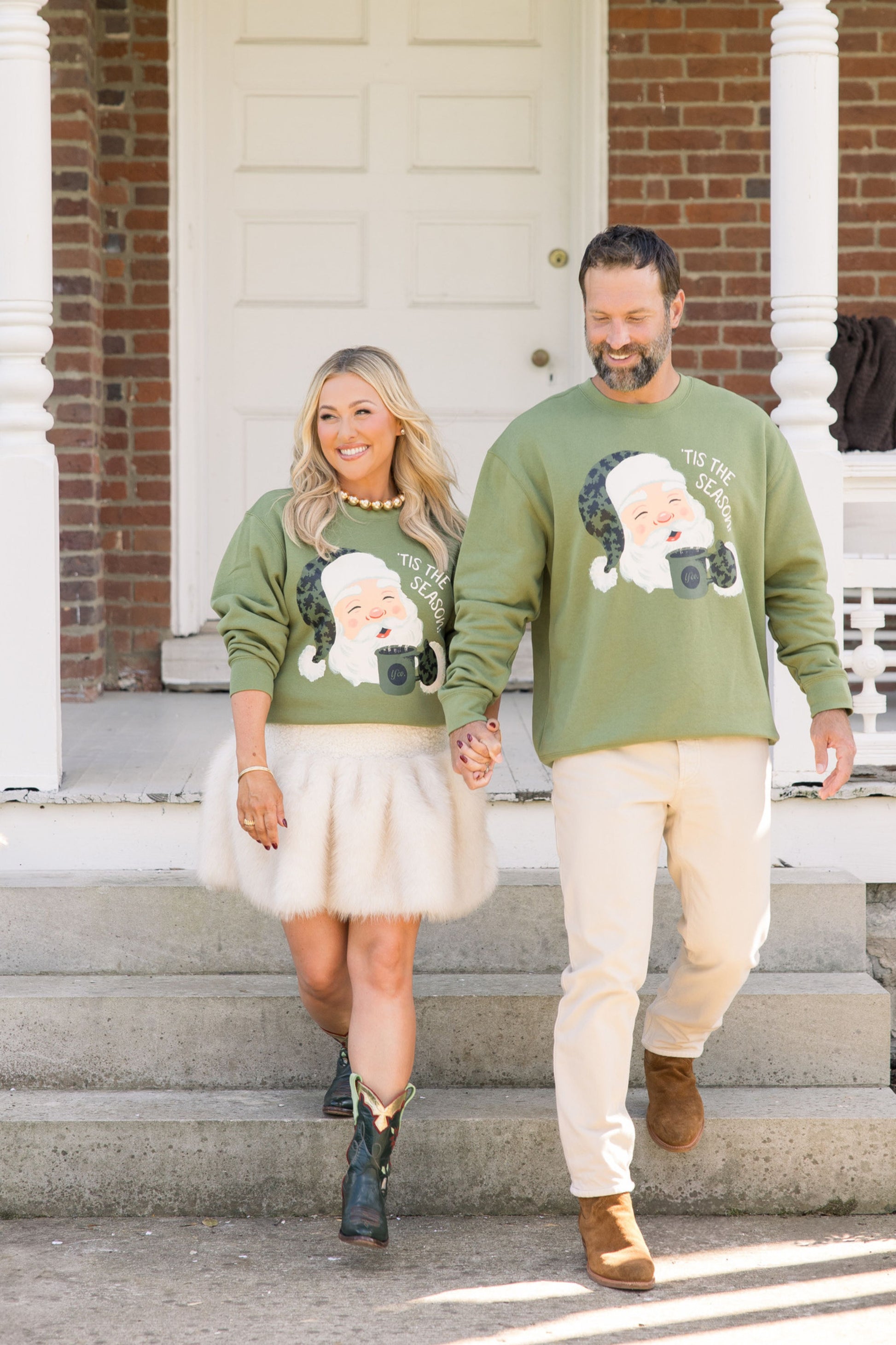 Man and woman walking on steps wearing green sweaters with Santa Claus graphics.
