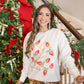 Woman wearing a festive sweater with Christmas decorations in a decorated room.