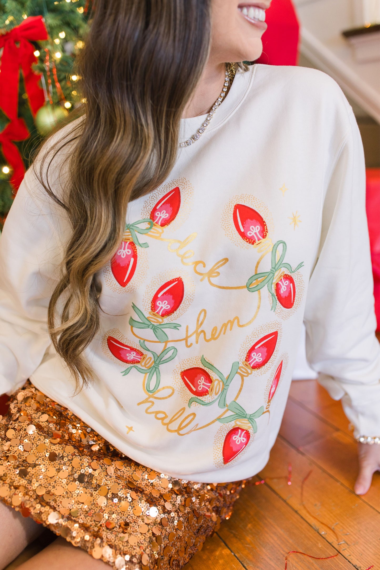 Person wearing a white sweatshirt with red and green designs in a festive setting