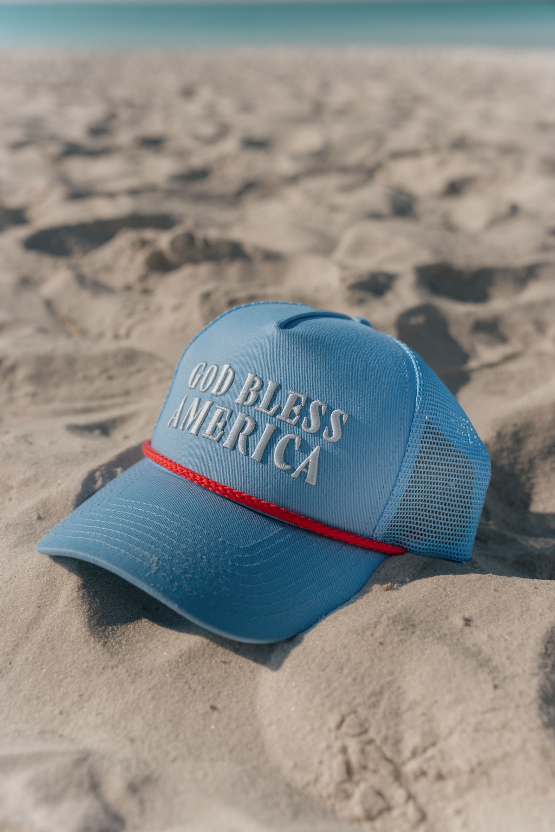 blue hat with god bless america on the front on the beach 