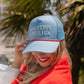 god bless america hat on woman with red sweater in front of palm trees