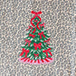 Leopard print shirt with a Christmas tree design featuring red bows on a textured surface.