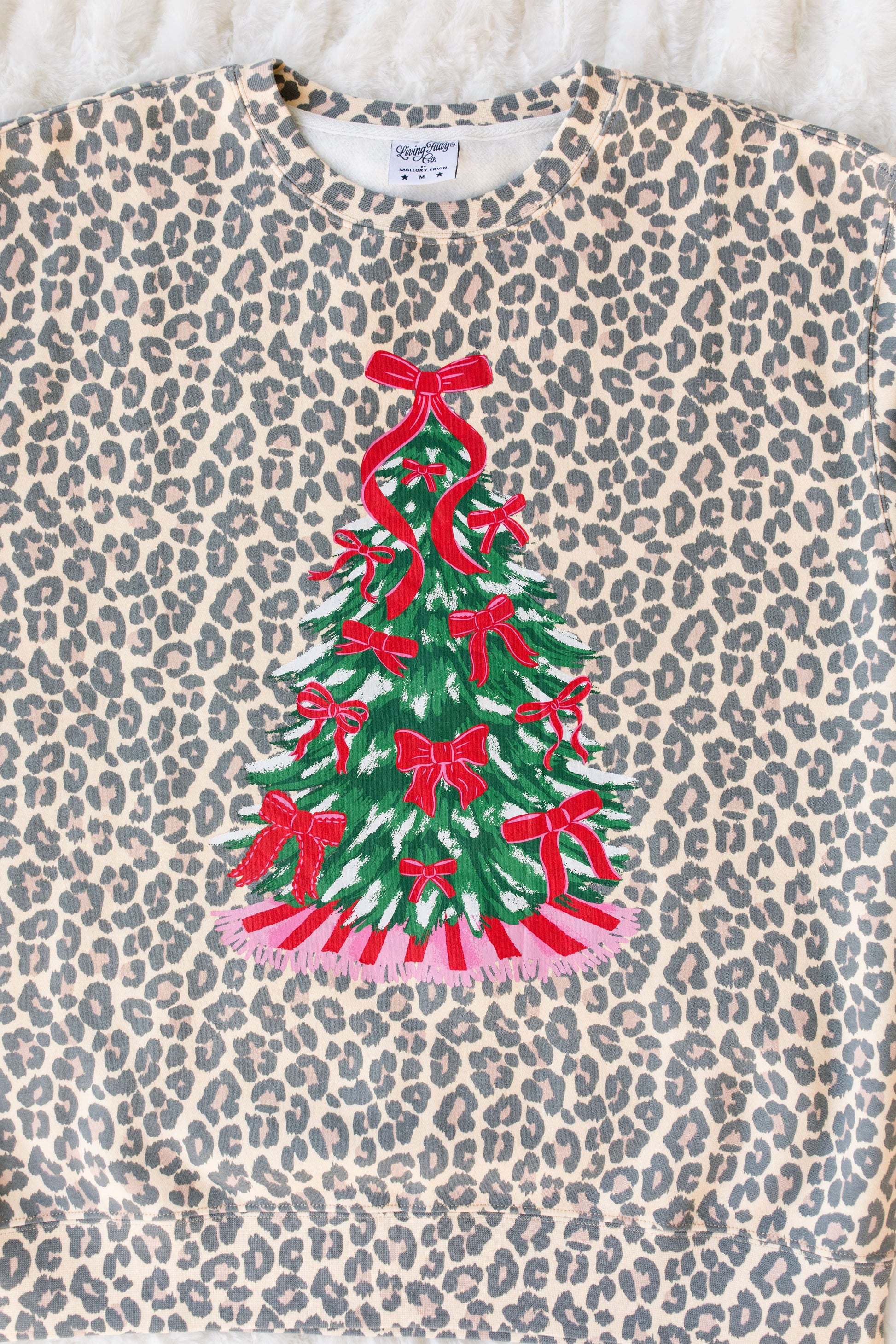 Leopard print shirt with a Christmas tree design featuring red bows on a textured surface.