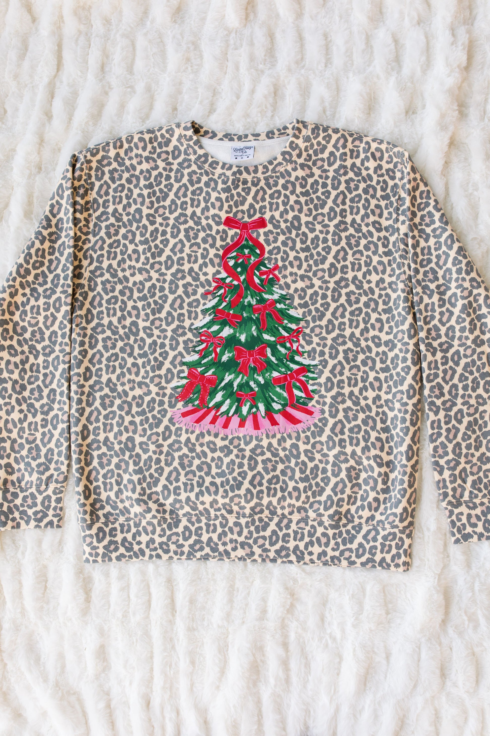 Leopard print sweater with a Christmas tree design on a textured surface