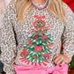 Person wearing a leopard print sweater with a Christmas tree design, standing in front of a decorated background.